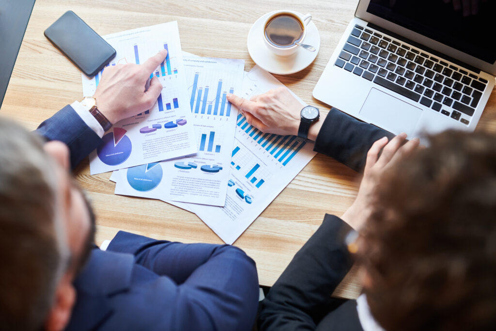 Geschäftsleute analysieren IT-Performance-Diagramme und diskutieren ROI am Konferenztisch.
