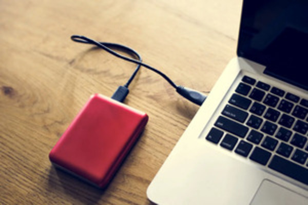 Rote externe Festplatte an ein MacBook angeschlossen.