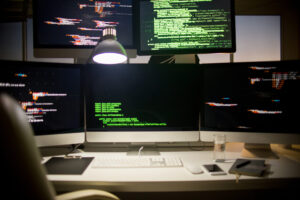 Mehrere Monitore mit Code auf einem Schreibtisch, vorbereitet für Penetrationstests.