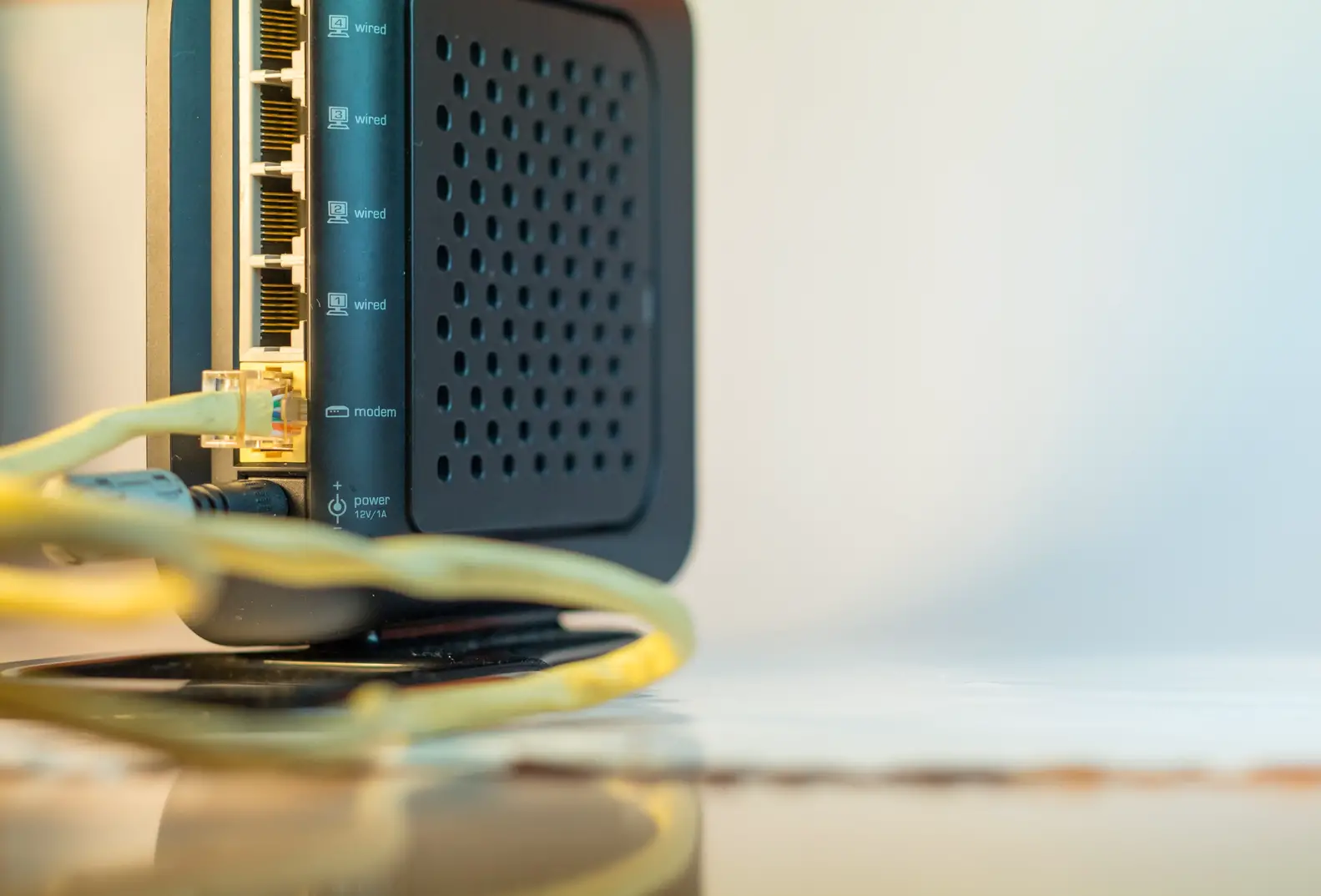 Rückansicht eines schwarzen Routers mit mehreren angeschlossenen gelben Netzwerkkabeln.